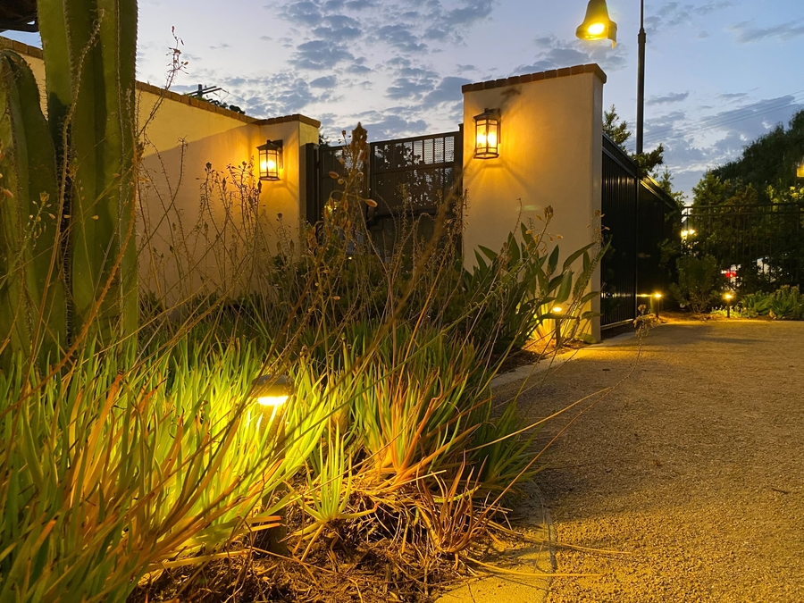 An outdoor area illuminated by landscape lighting that casts shadows and adds depth to the space.