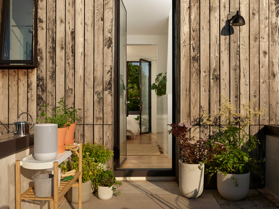 A wireless Sonos speaker in an outdoor space, surrounded by plants.