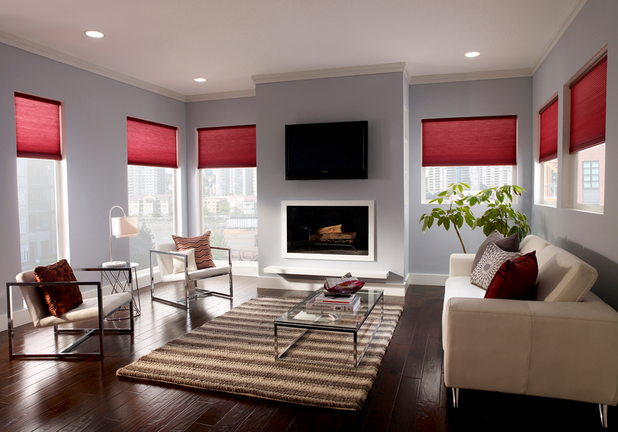 A modern living room with red Serena roller shades by Lutron halfway down the windows.